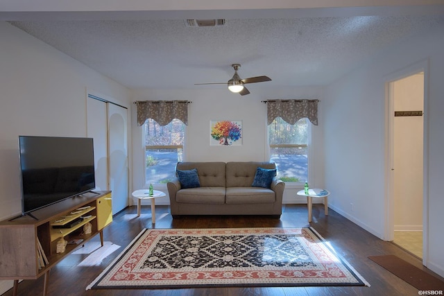 living area with dark wood finished floors, visible vents, ceiling fan, a textured ceiling, and baseboards