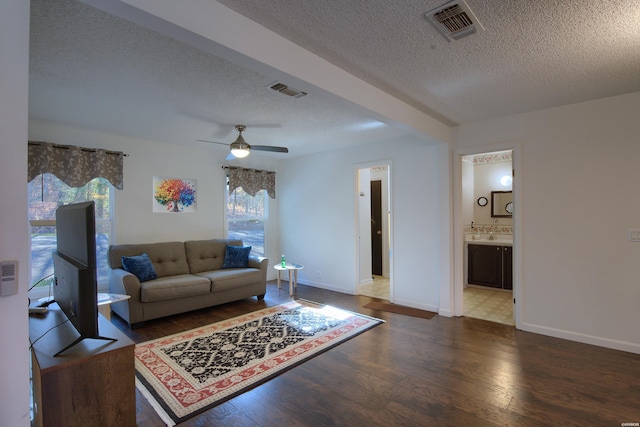 living room featuring baseboards, visible vents, ceiling fan, wood finished floors, and a textured ceiling