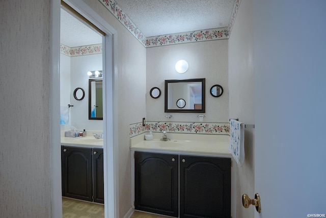 bathroom featuring a textured ceiling, two vanities, and a sink