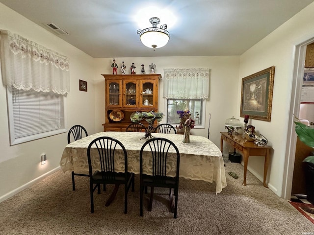 dining area featuring baseboards, visible vents, and dark colored carpet