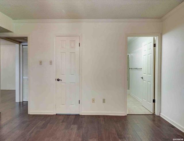 unfurnished bedroom with dark wood-style floors, crown molding, connected bathroom, a textured ceiling, and baseboards