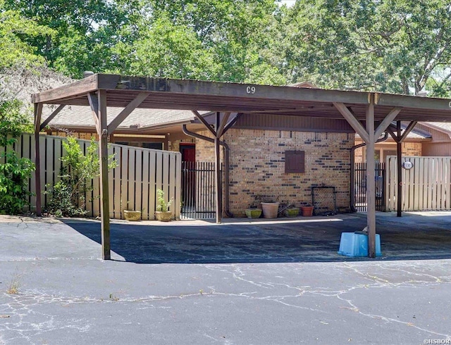 exterior space with covered parking, a gate, and fence