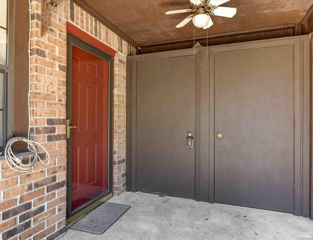 property entrance with ceiling fan and brick siding