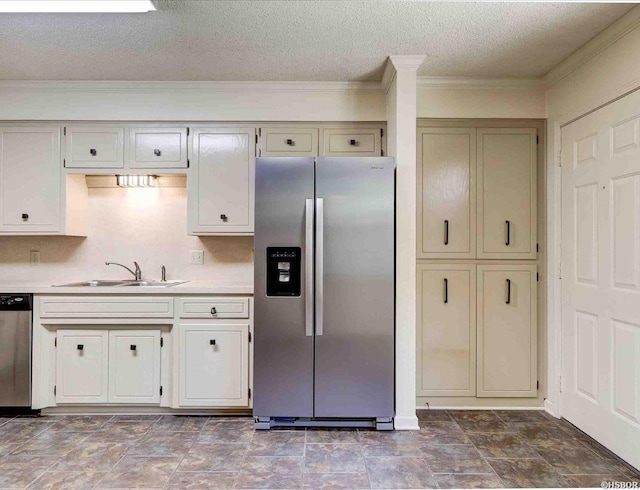 kitchen featuring appliances with stainless steel finishes, light countertops, crown molding, a textured ceiling, and a sink