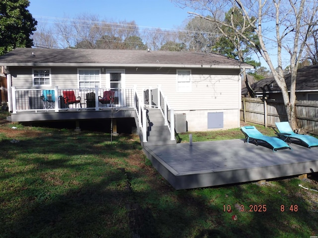 back of house featuring a wooden deck, a lawn, and fence