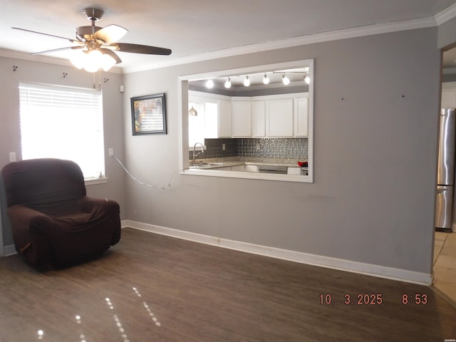 living area with ceiling fan, wood finished floors, baseboards, and ornamental molding