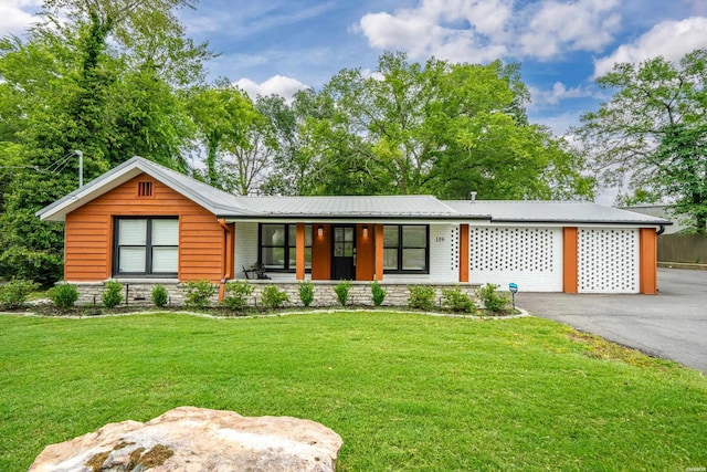 view of front of property featuring a porch, a front yard, metal roof, and driveway