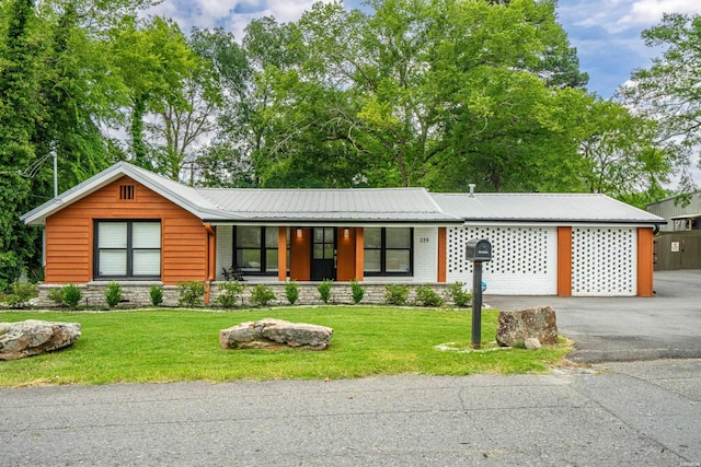 view of front of property featuring a front yard, metal roof, and driveway