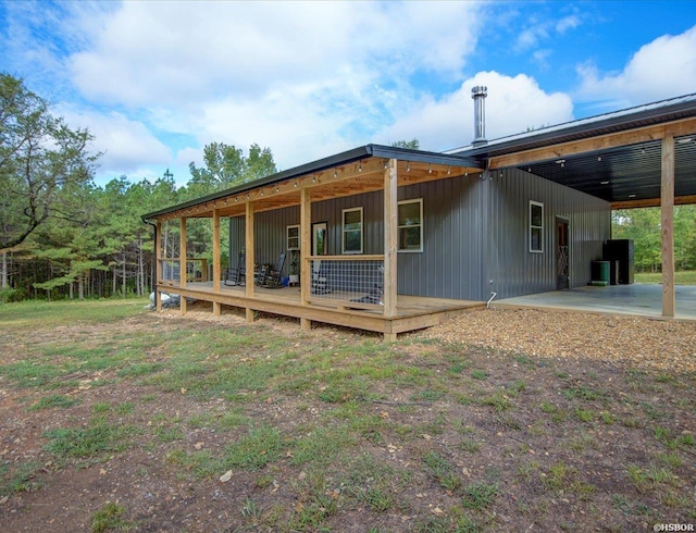 back of house with an attached carport, central air condition unit, and covered porch