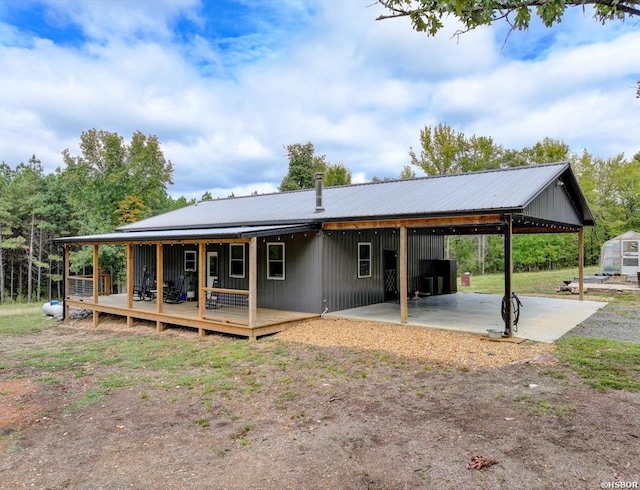 rear view of property featuring metal roof, an attached carport, and central AC