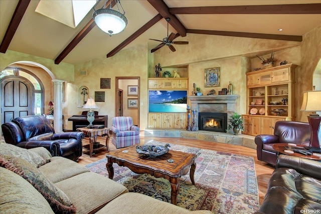 living area featuring decorative columns, arched walkways, beam ceiling, and light wood-type flooring