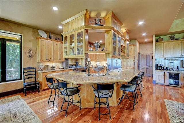 kitchen featuring backsplash, light brown cabinets, light wood finished floors, and beverage cooler