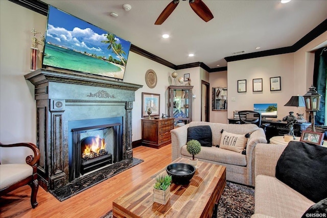 living room featuring visible vents, a fireplace, wood finished floors, ornamental molding, and a ceiling fan