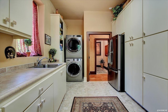 clothes washing area featuring stacked washer and clothes dryer, a sink, and laundry area