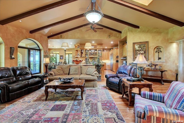 living area featuring ceiling fan, high vaulted ceiling, light wood-style floors, and beam ceiling