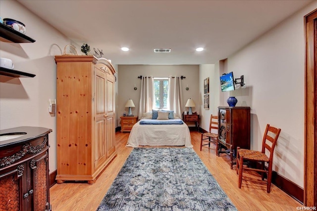 bedroom with baseboards, visible vents, and light wood-style flooring