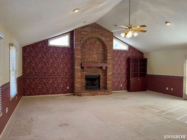 unfurnished living room featuring carpet flooring, a textured ceiling, and vaulted ceiling