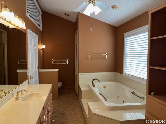 bathroom featuring tile patterned floors, visible vents, a ceiling fan, a tub with jets, and lofted ceiling