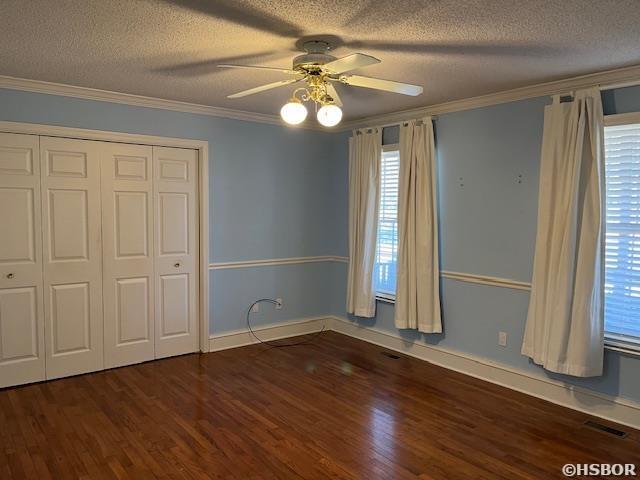 unfurnished bedroom with visible vents, a textured ceiling, wood finished floors, and ornamental molding