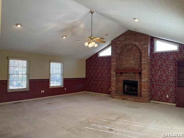 unfurnished living room featuring plenty of natural light, wainscoting, wallpapered walls, and lofted ceiling