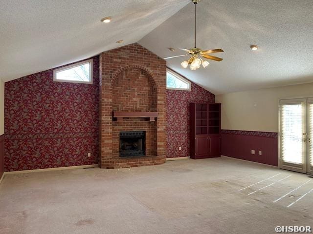 unfurnished living room with a fireplace, a textured ceiling, lofted ceiling, and carpet floors