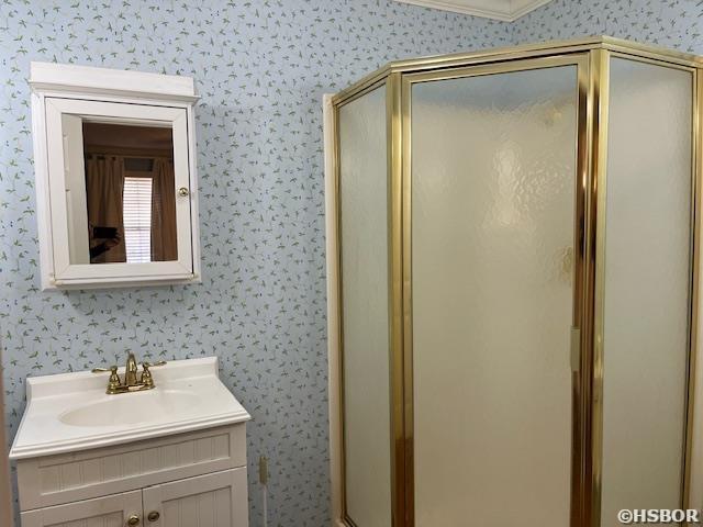 bathroom with a stall shower, wallpapered walls, and vanity