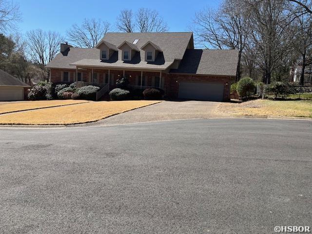 cape cod house featuring an attached garage and driveway