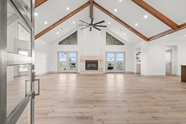 unfurnished living room featuring high vaulted ceiling, light wood-type flooring, french doors, and beam ceiling