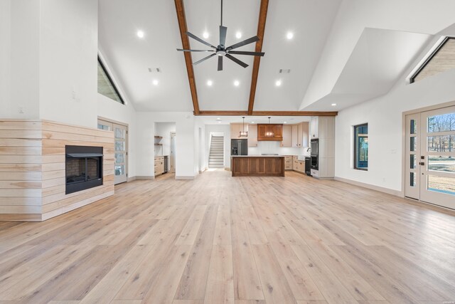 unfurnished living room with baseboards, a ceiling fan, light wood-type flooring, a fireplace, and high vaulted ceiling