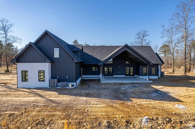 view of front of property with a shingled roof, board and batten siding, and central AC unit