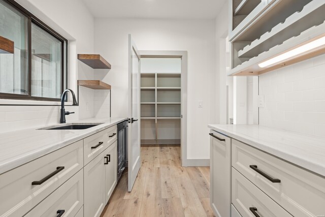 kitchen with light stone countertops, white cabinets, a sink, and open shelves