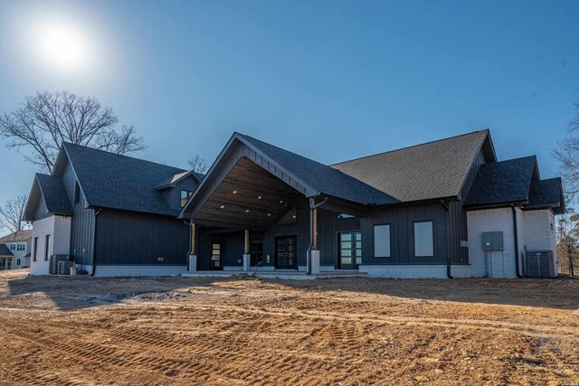 back of property featuring central AC, brick siding, and board and batten siding