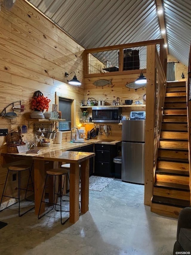 kitchen featuring a peninsula, stainless steel appliances, concrete floors, and a sink