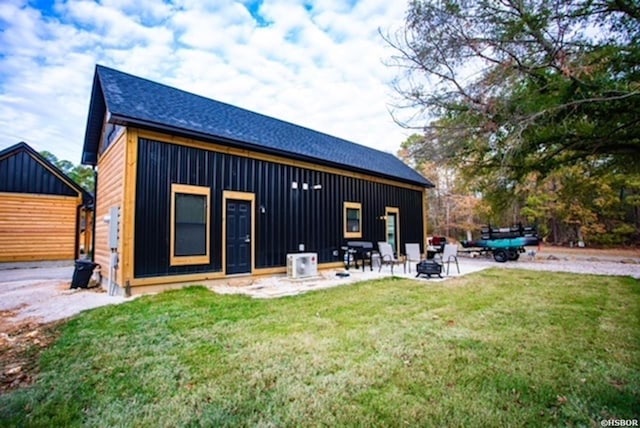 back of house with a patio area, a lawn, board and batten siding, and roof with shingles