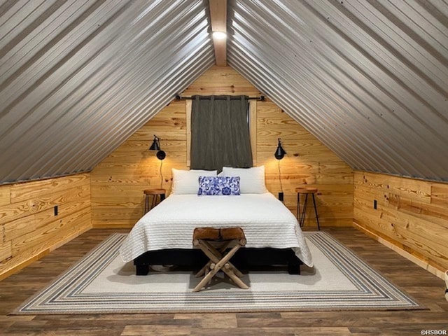 bedroom with wood finished floors, lofted ceiling, and wood walls