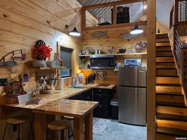 kitchen with wooden walls, open shelves, a peninsula, a sink, and stainless steel appliances