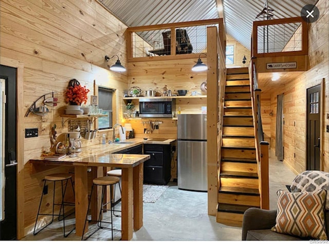 kitchen featuring open shelves, wooden walls, appliances with stainless steel finishes, and a peninsula