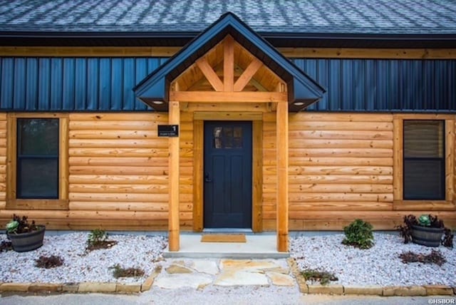 view of exterior entry featuring metal roof and a shingled roof