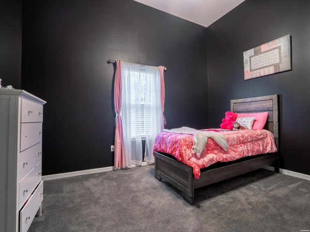 bedroom with dark colored carpet and baseboards