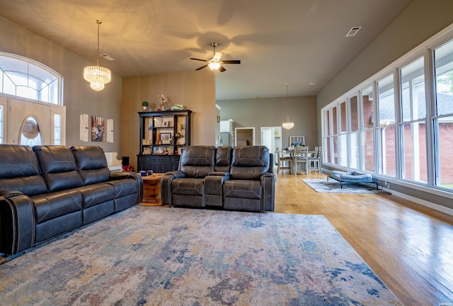 living area featuring a chandelier, a high ceiling, visible vents, and light wood-style floors