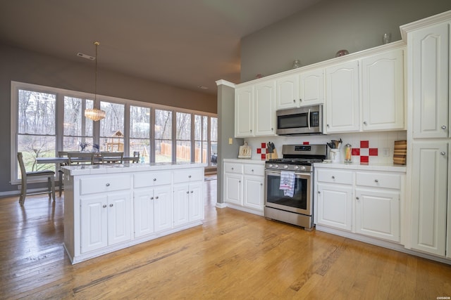 kitchen with hanging light fixtures, white cabinetry, stainless steel appliances, and light countertops