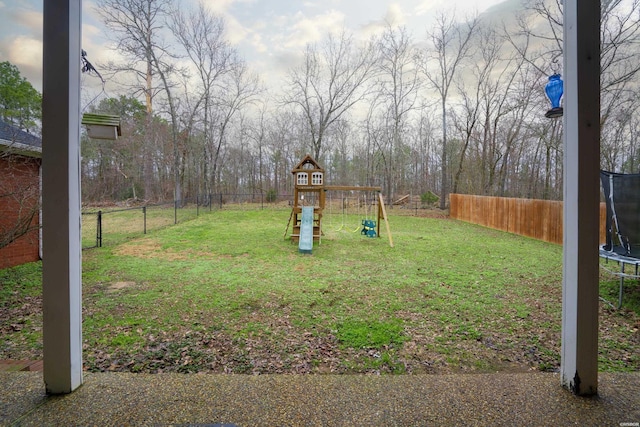 view of yard featuring a trampoline, a playground, and a fenced backyard