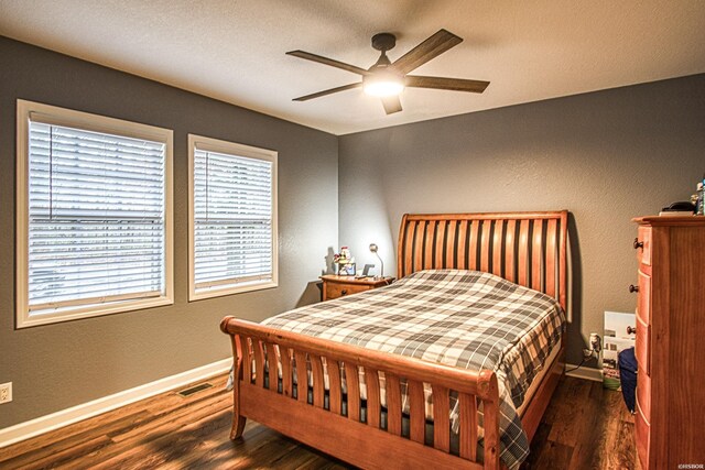 bedroom featuring baseboards, visible vents, ceiling fan, and dark wood-style flooring