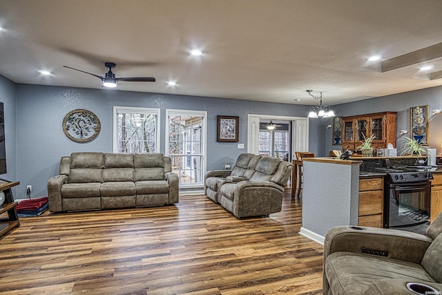 living room featuring recessed lighting, dark wood-style flooring, baseboards, and ceiling fan with notable chandelier