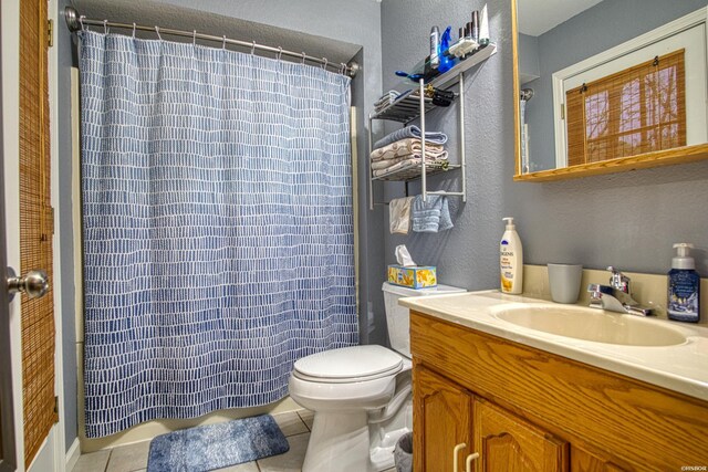 full bath with a shower with curtain, vanity, toilet, and tile patterned floors