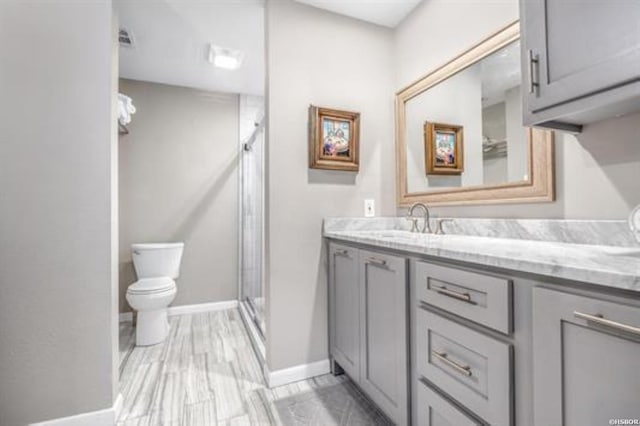 full bathroom with vanity, a shower stall, toilet, and baseboards