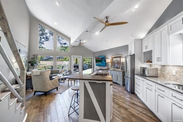 kitchen with ceiling fan, a breakfast bar area, stainless steel appliances, and dark wood finished floors