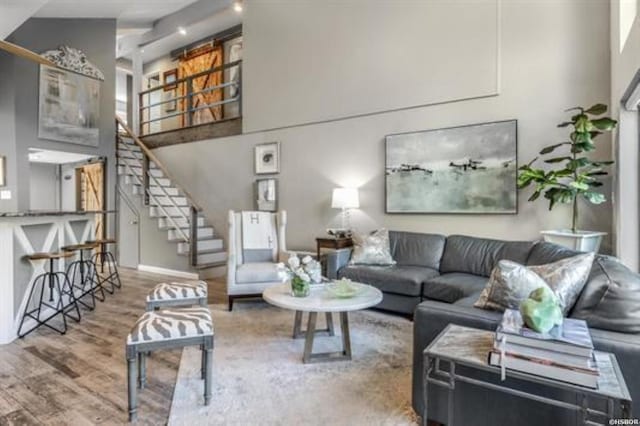 living room featuring a high ceiling, stairway, and wood finished floors