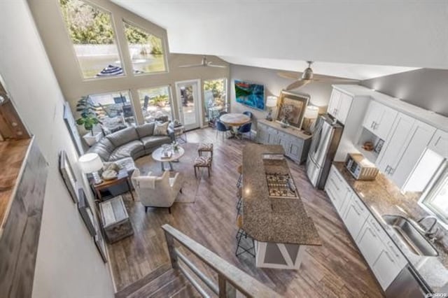 living area with dark wood-style floors, a high ceiling, and a ceiling fan