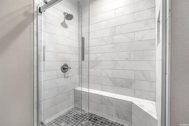 bathroom with a textured wall and a shower stall